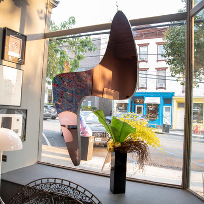 Modern interior design with custom mirror hanging in window, and a view of a street outside.