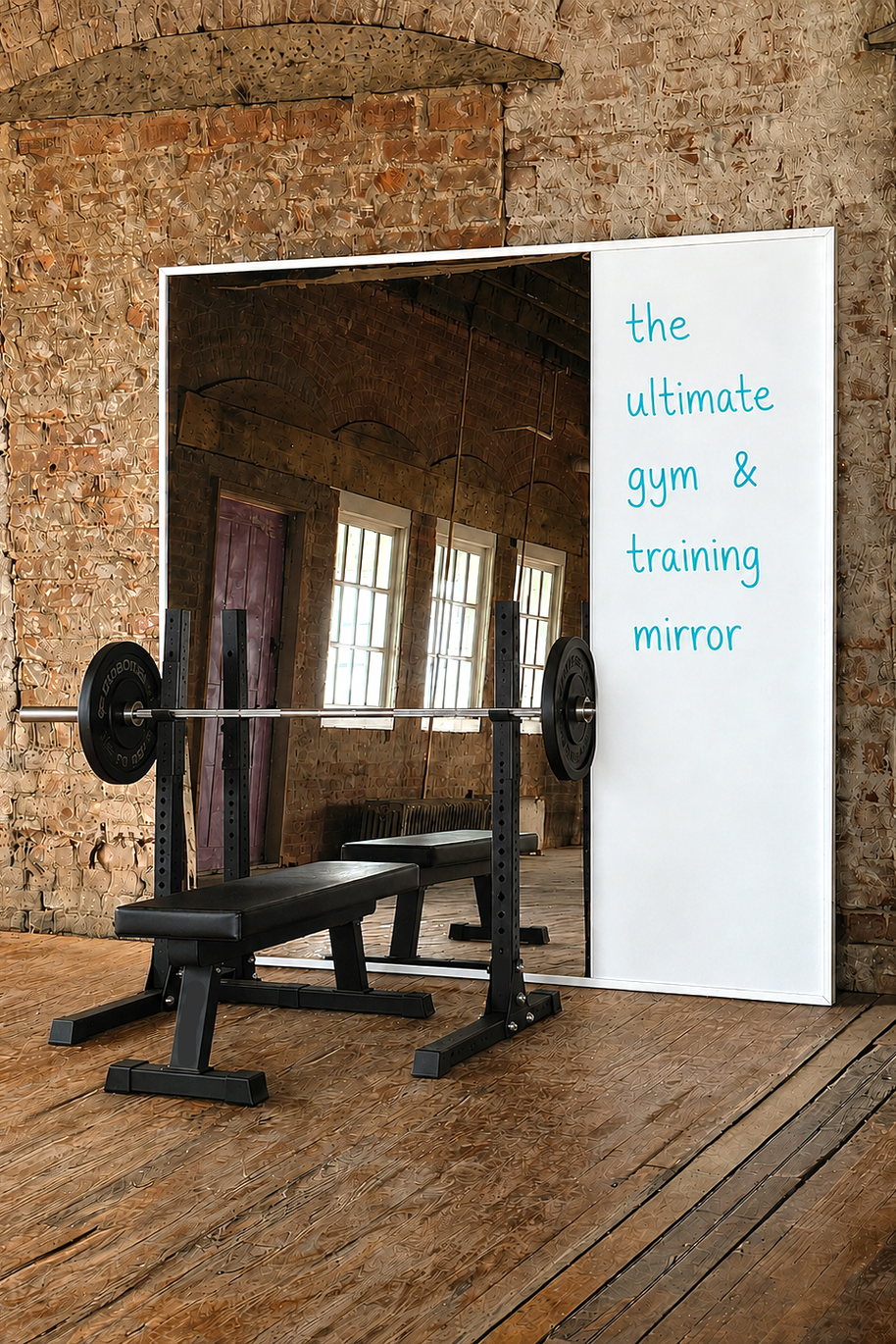 Gym mirror with whiteboard on a brick wall, featuring a barbell and bench.