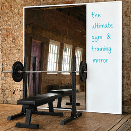 Gym mirror with whiteboard on a brick wall, featuring a barbell and bench.