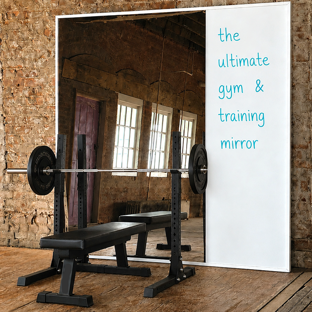 Gym mirror with whiteboard on a brick wall, featuring a barbell and bench.