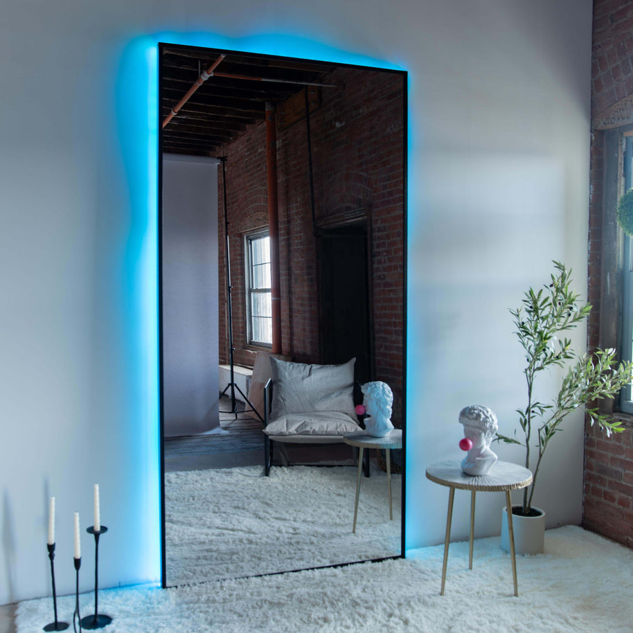 Wall mounted mirror with black wood frame and backlighting in a spacious living room