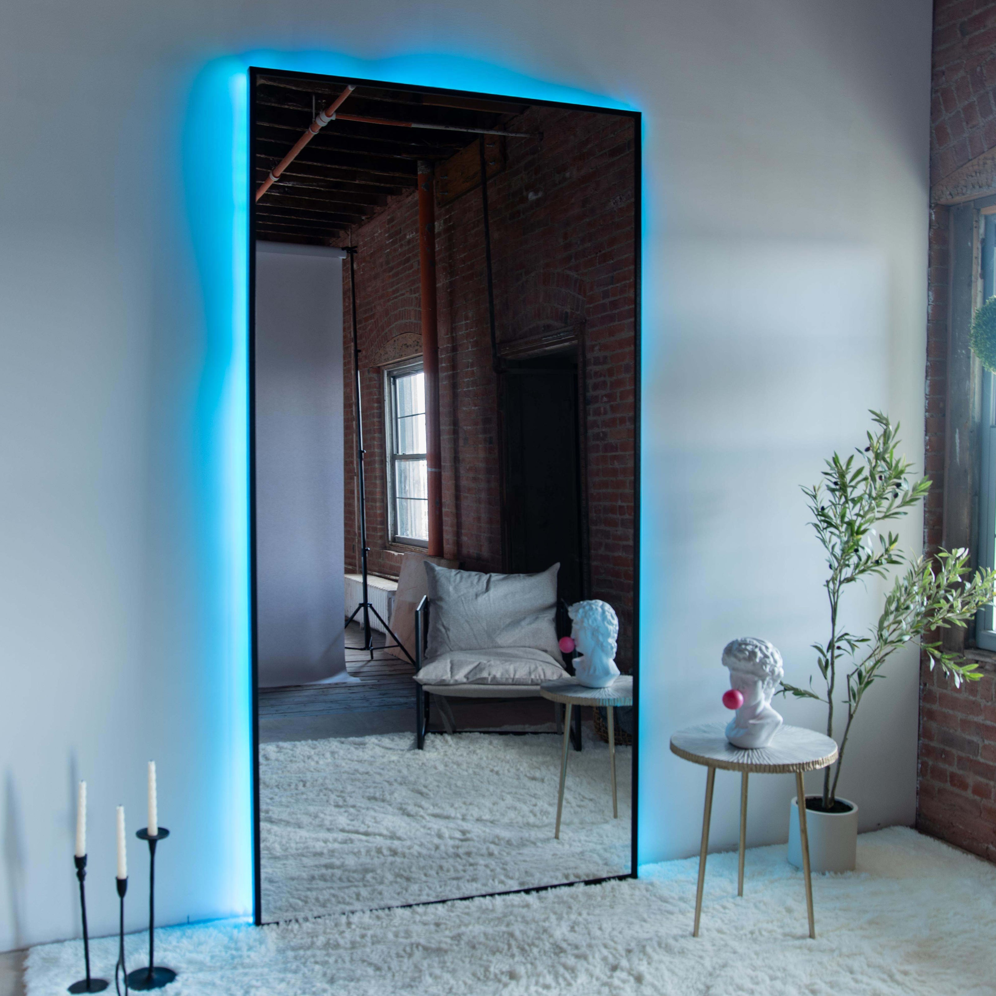 Wall mounted mirror with black wood frame and backlighting in a spacious living room