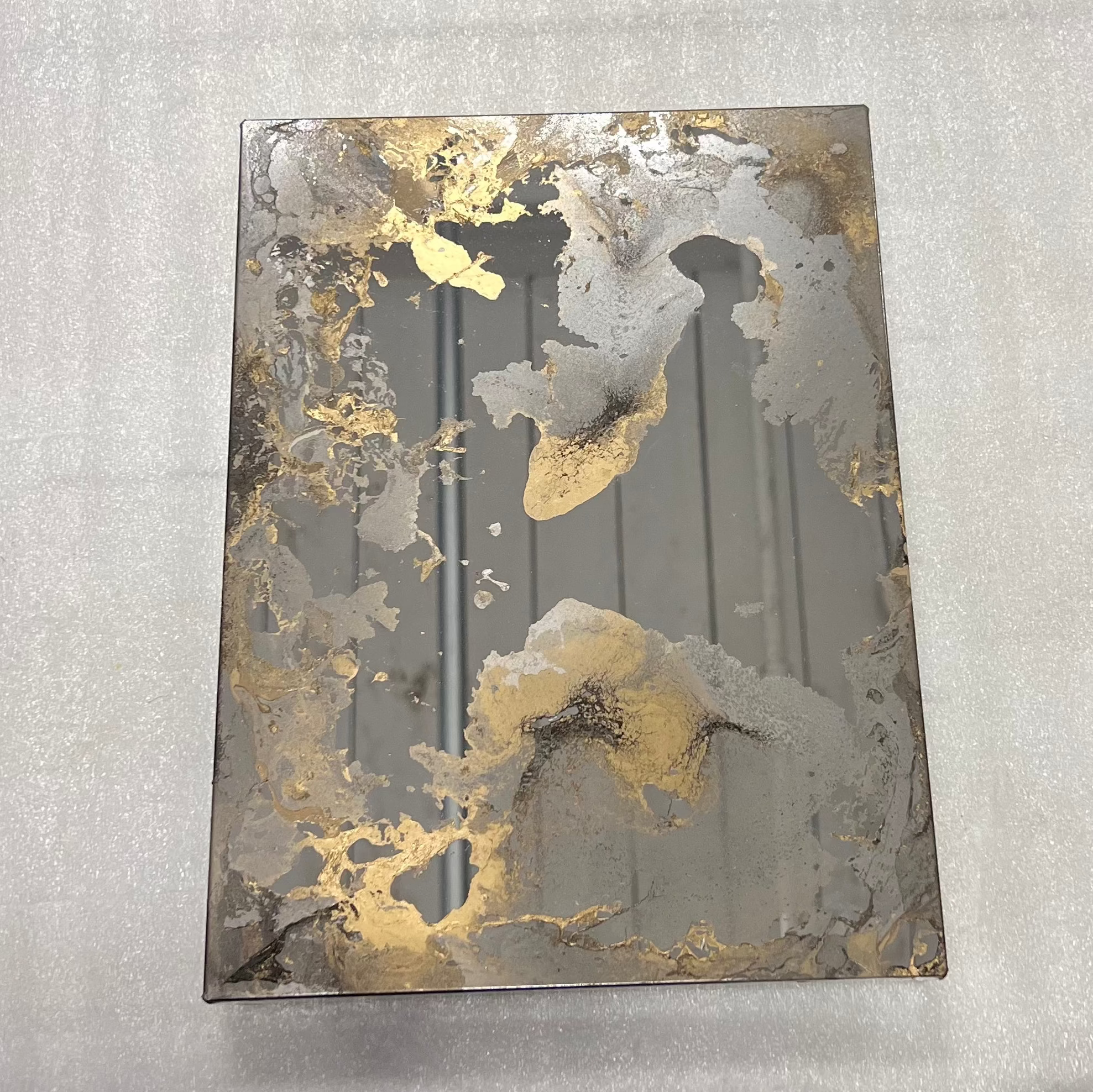 Gold antique mirror sample with gold decorative paint on grey background