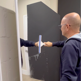 Person cleaning a large litemirror with a squeegee