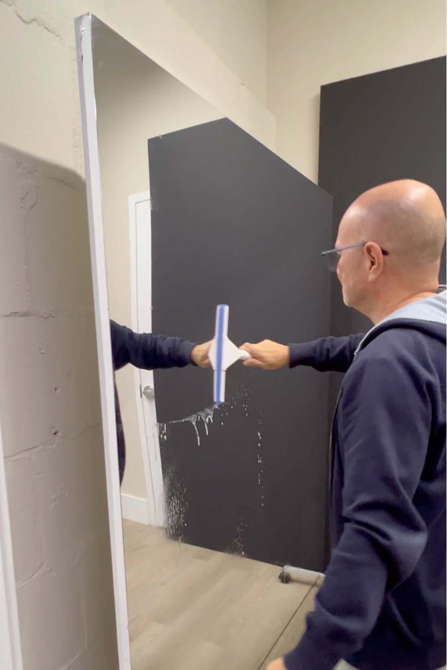 Person cleaning a large litemirror with a squeegee