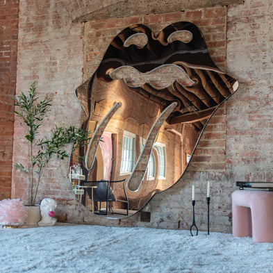 Large decorative mirror with logo design on a brick wall