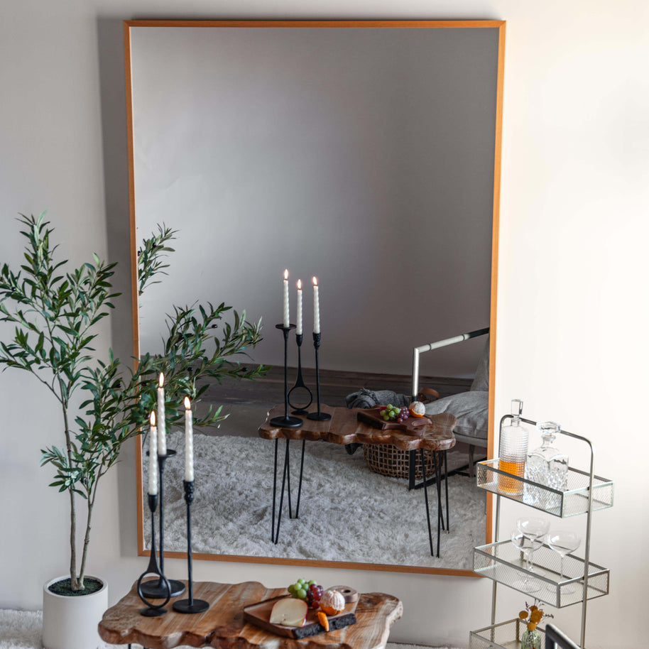 Modern living room with a large LiteMirror with a natural wood frame, candles, and decorative items.