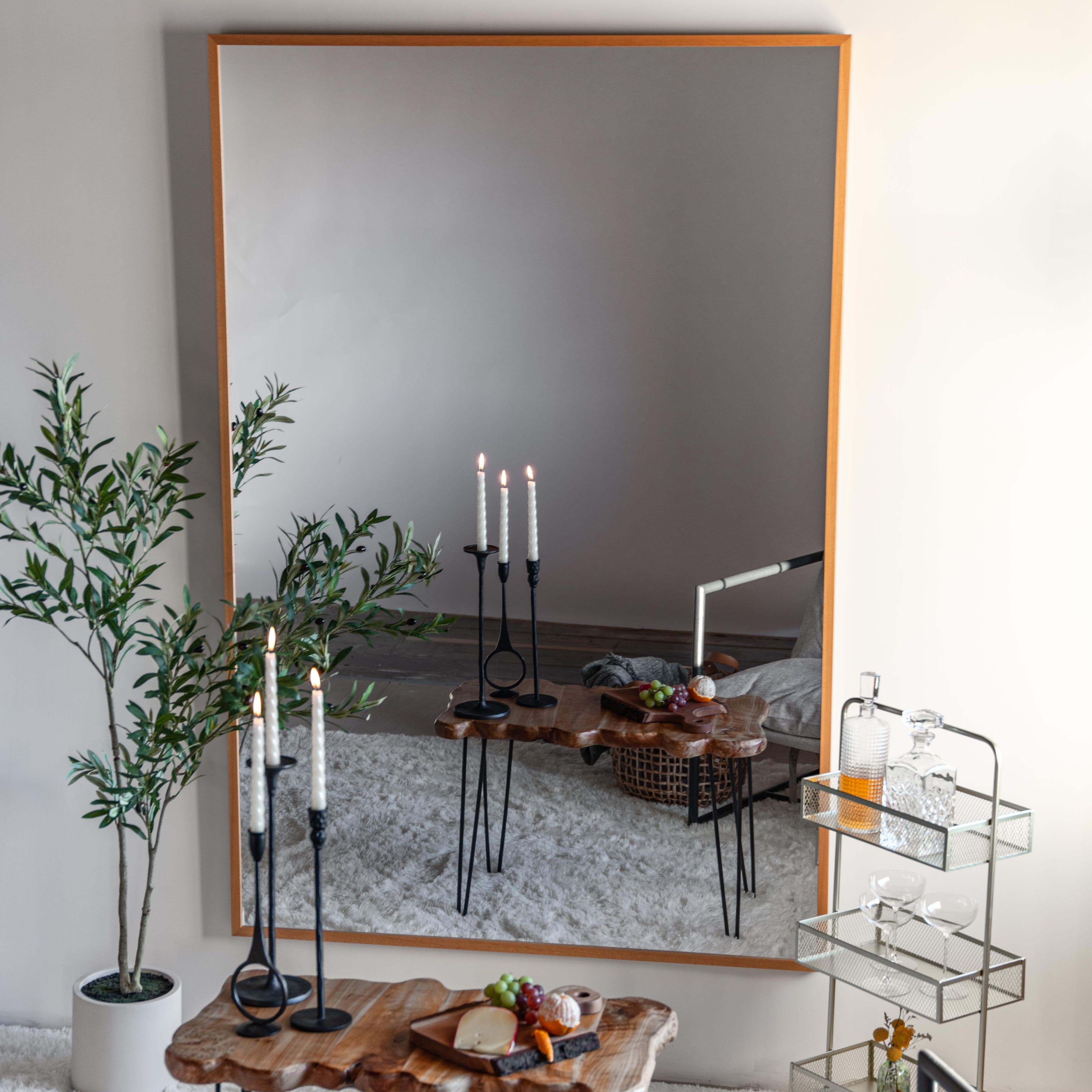 Modern living room with a large LiteMirror with a natural wood frame, candles, and decorative items.