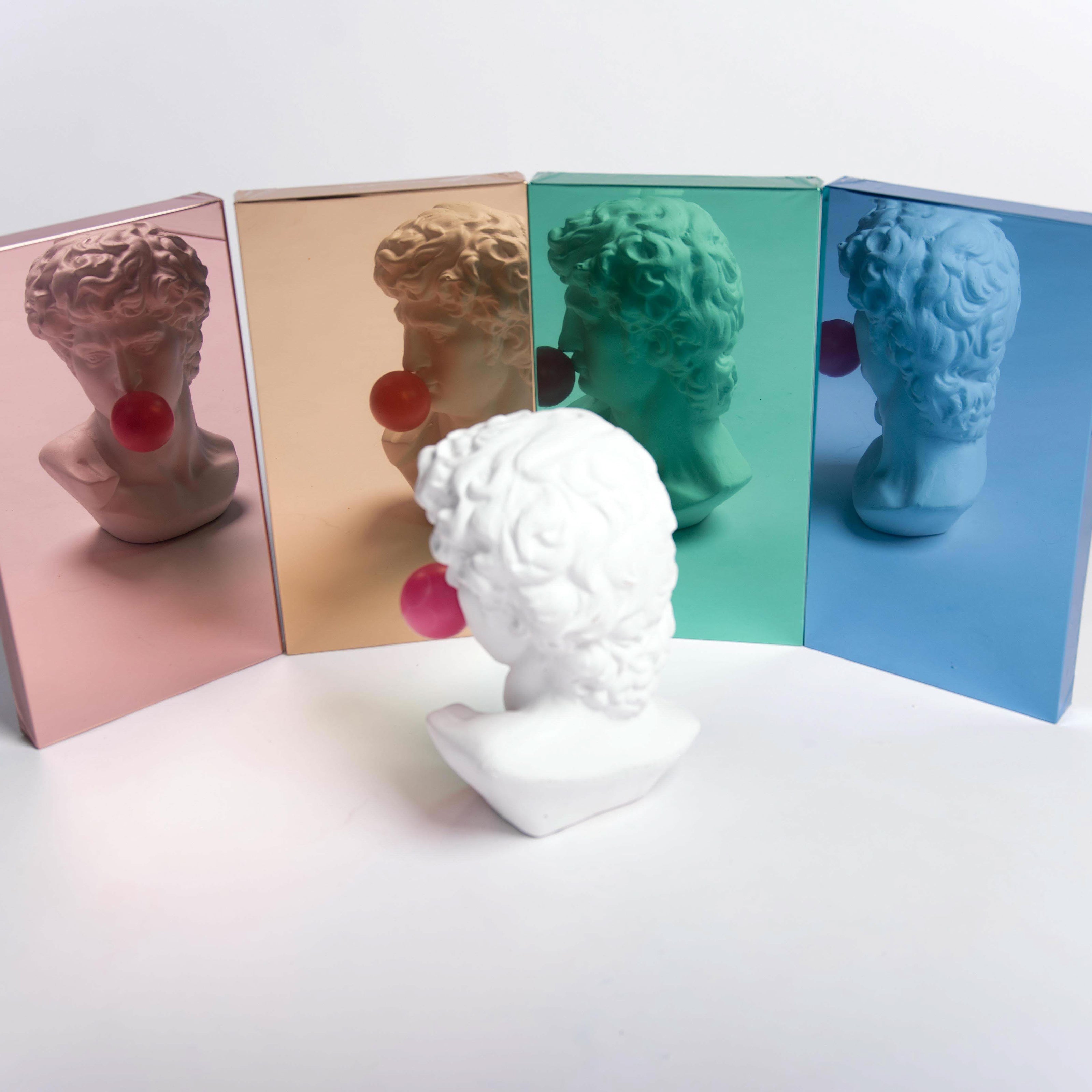White ceramic bust in front of four film color samples with bust reflection on white background