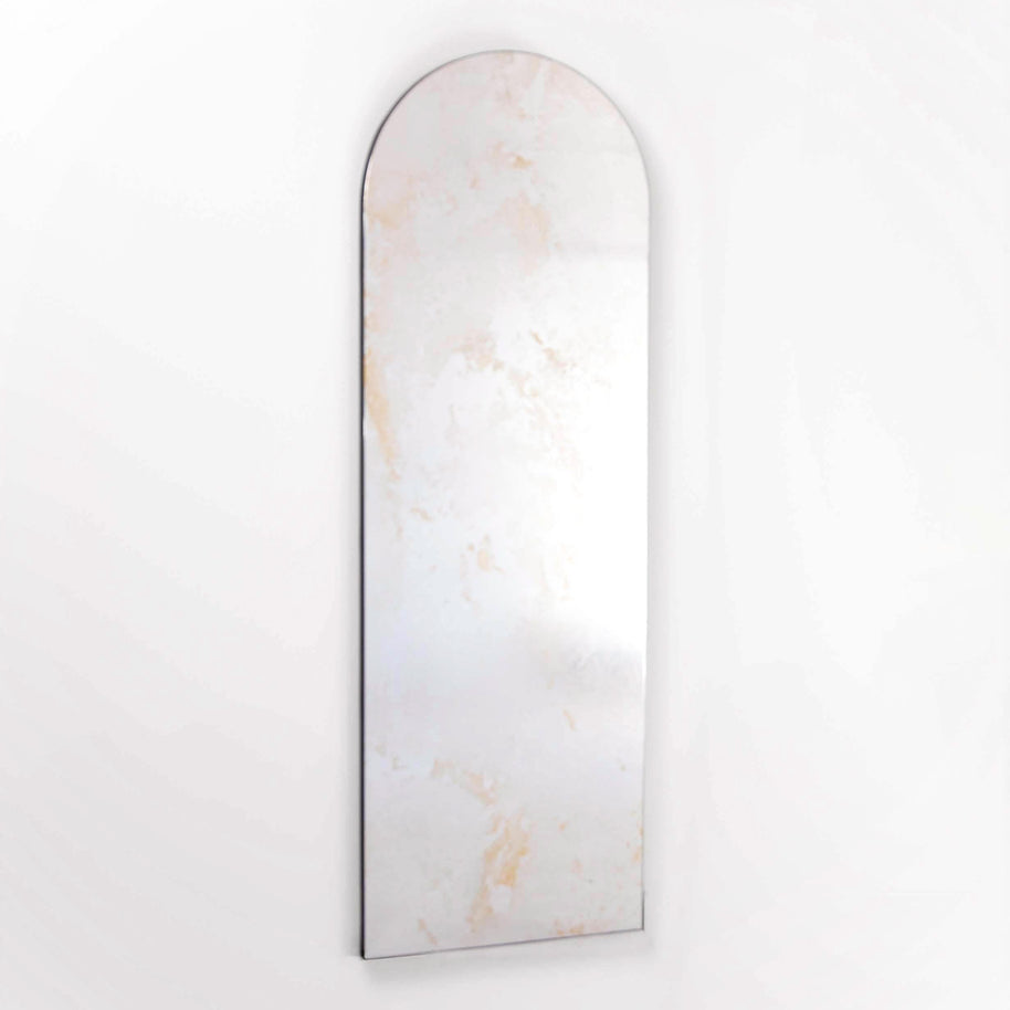 Arched mirror with marble-like antique patina on a white background