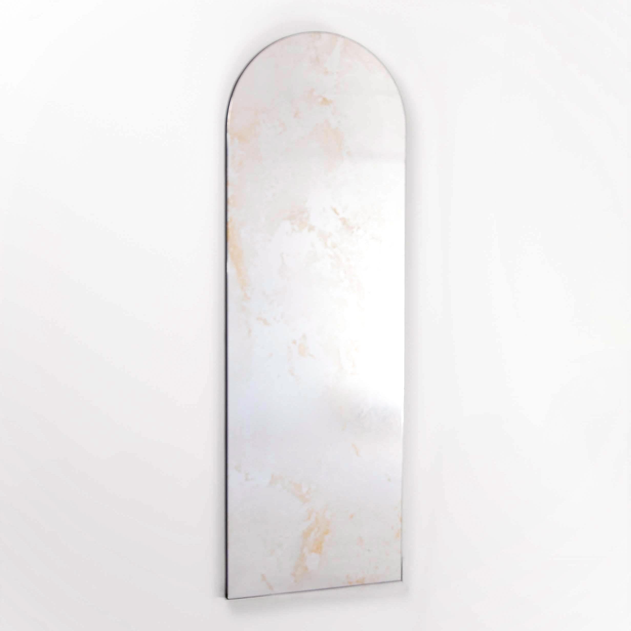 Arched mirror with marble-like antique patina on a white background