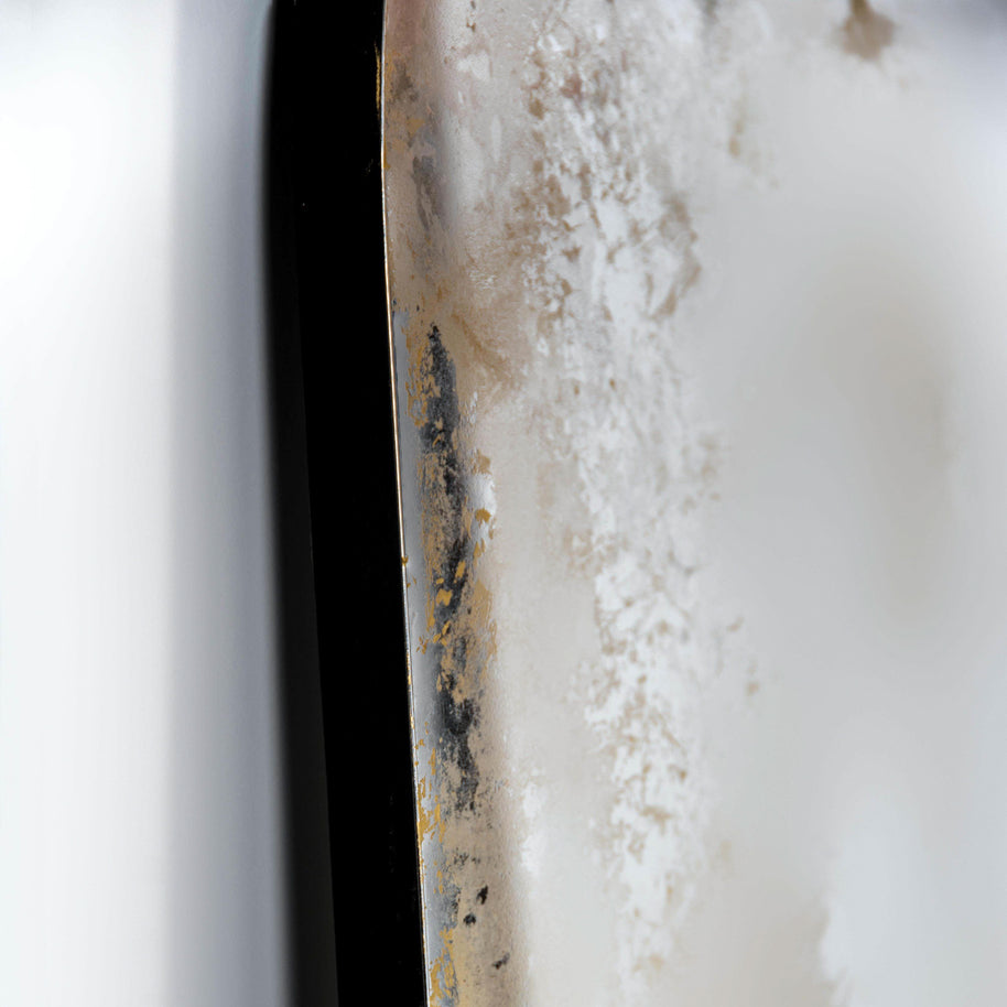 Close-up of gold antiqued arched mirror with black edging 