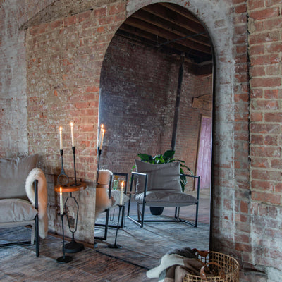 Arched mirror leaning against a brick wall in living room