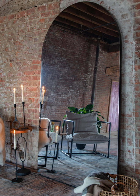Arched mirror leaning against a brick wall in living room