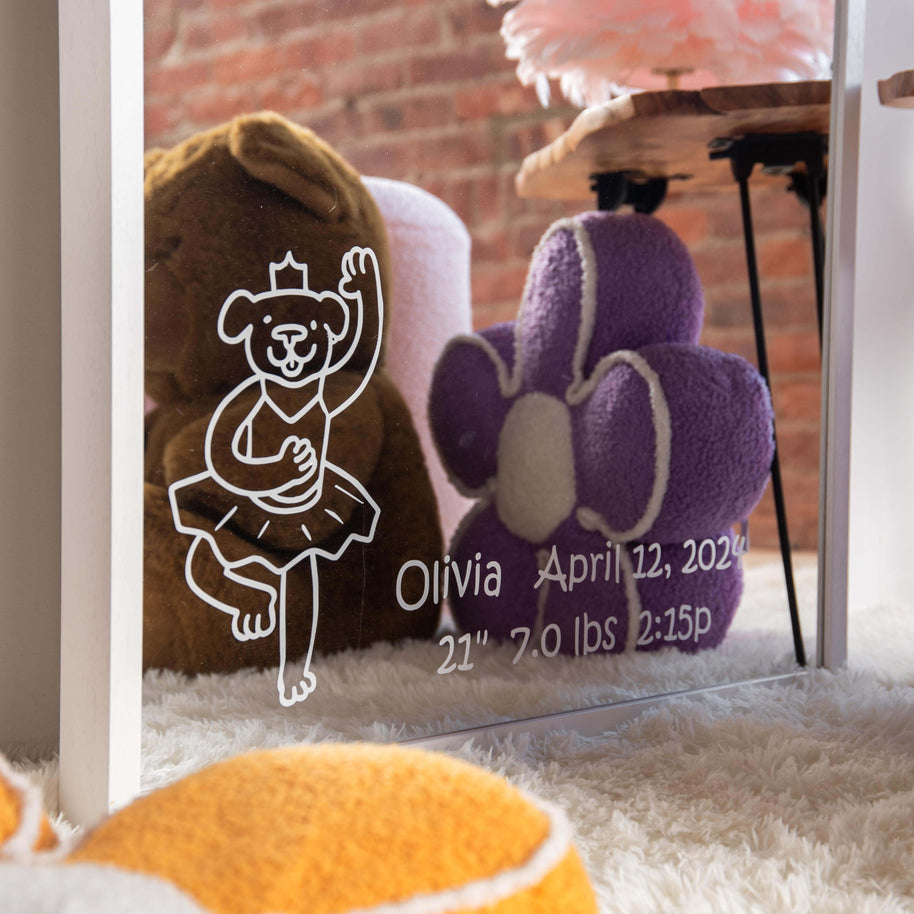 Decorative mirror with vinyl details of child's name and children's character, surrounded by plush toys.