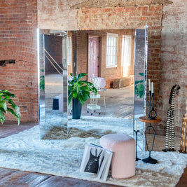 Large multi-panel mirror against a brick wall in a dressing room setting