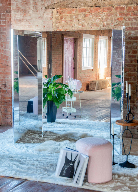 Large multi-panel mirror against a brick wall in a dressing room setting
