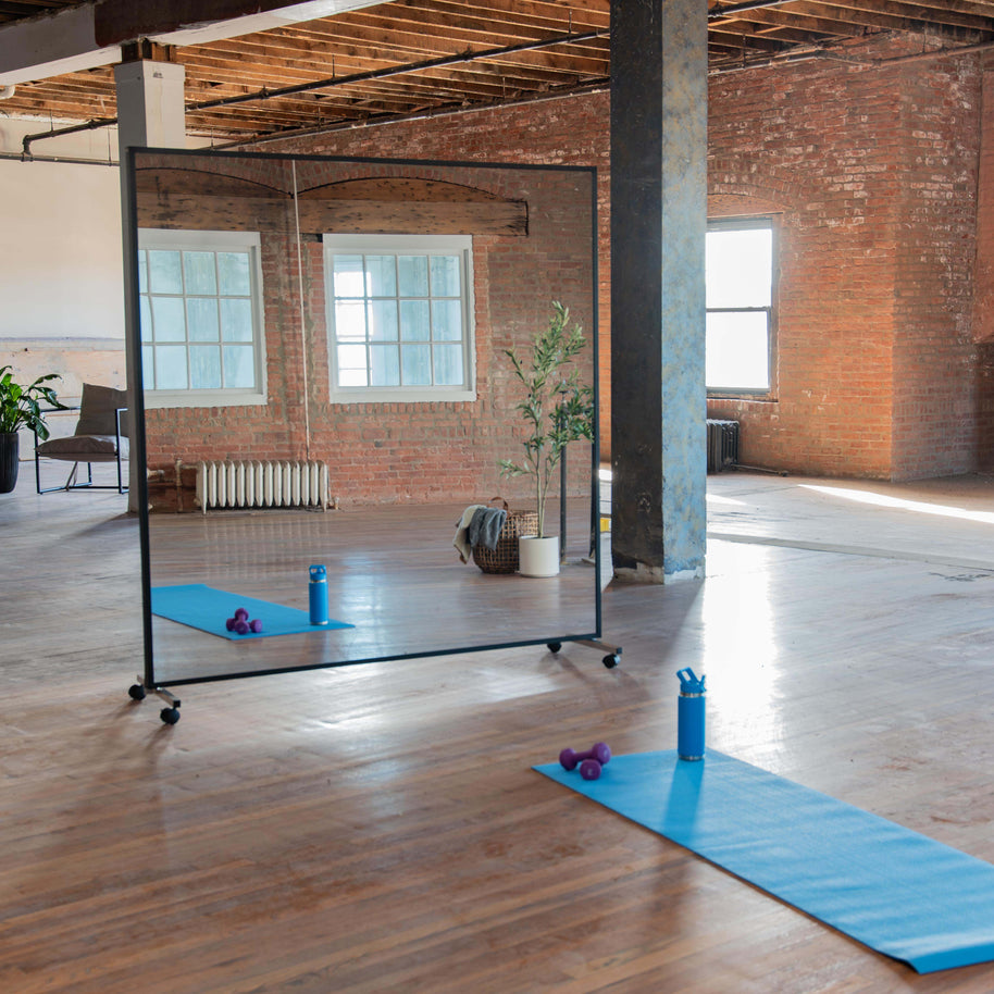 Portable mirror with black wood Fram end black rolling stands in a yoga studio setting