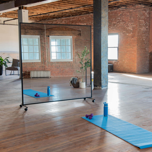 Portable mirror with black wood Fram end black rolling stands in a yoga studio setting