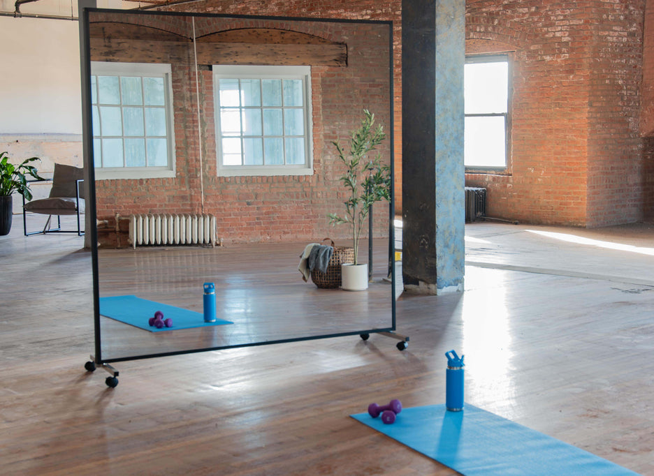 Portable mirror with black wood Fram end black rolling stands in a yoga studio setting