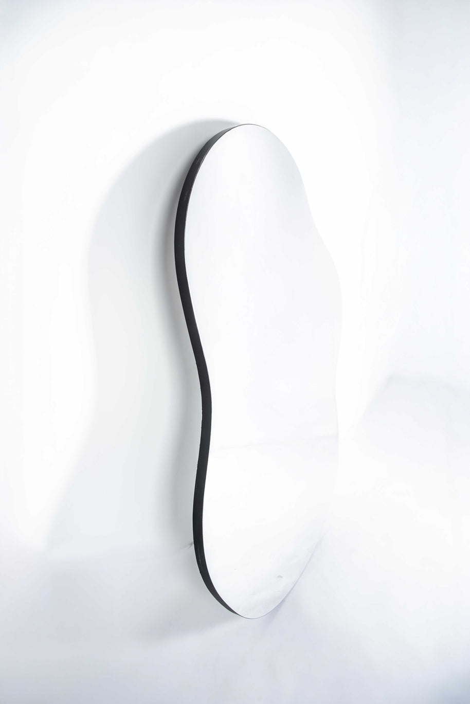 Irregular-shaped mirror with black edging on white background