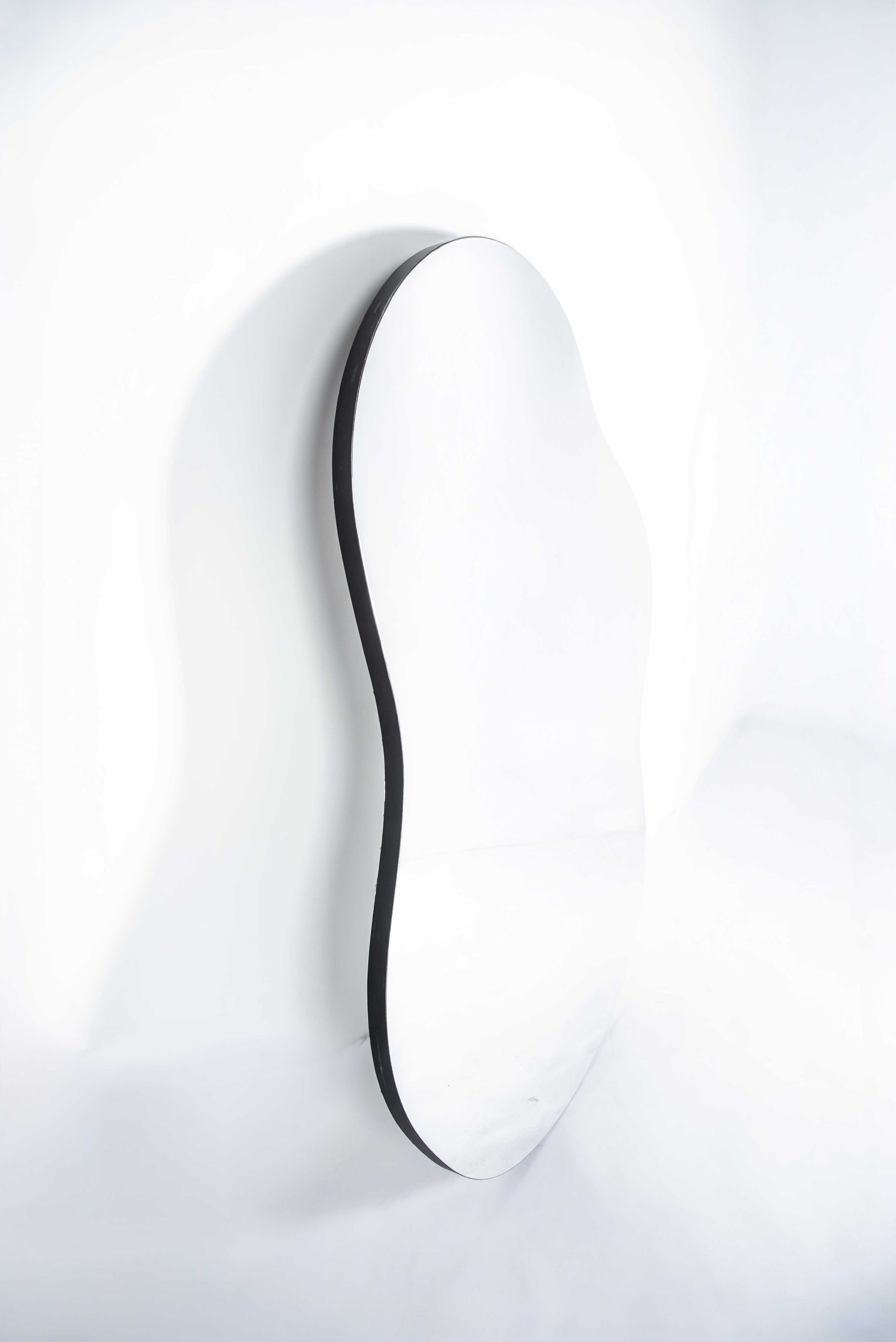 Irregular-shaped mirror with black edging on white background