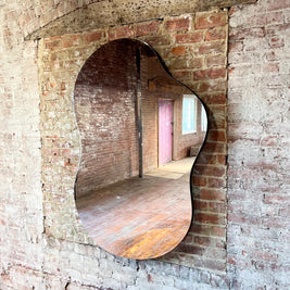Asymmetrical curved mirror on a brick wall
