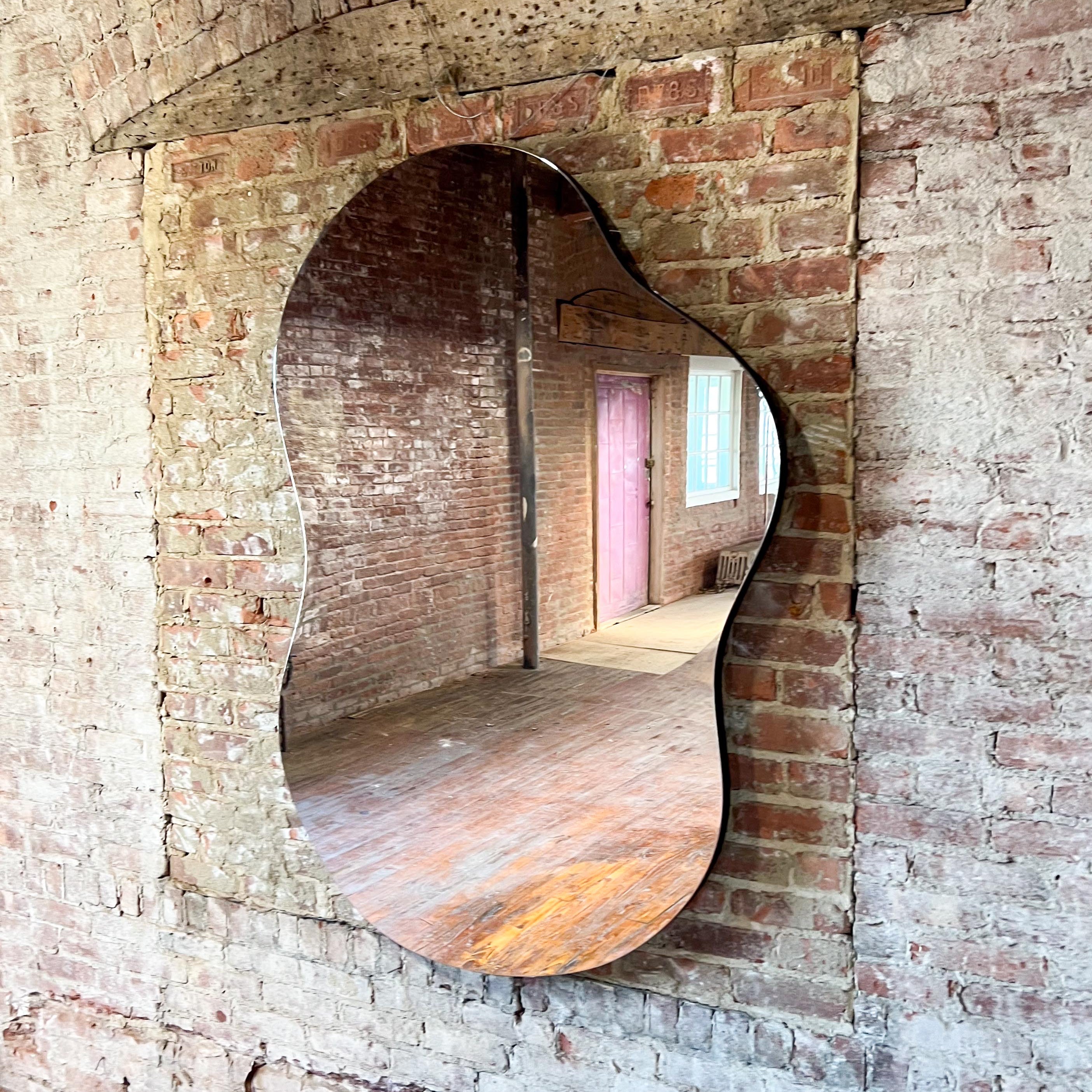 Asymmetrical curved mirror on a brick wall