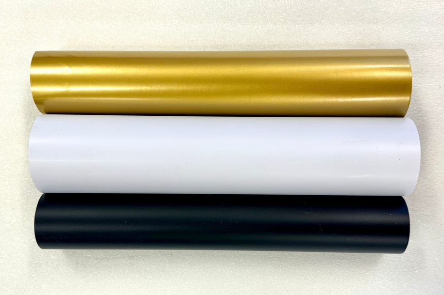 Three rolls of vinyl wrap in black, white, and gold on a white background